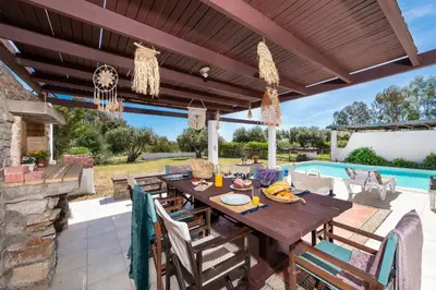 a patio with a wooden table and chairs and a pool at Lual Palette Rhodos in Afantou