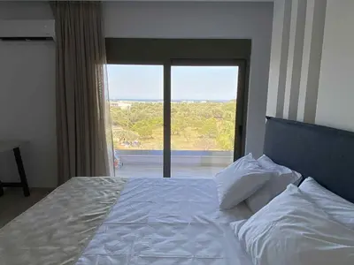 a bedroom with a white bed with a large window at Villa Kennedy in Faliraki