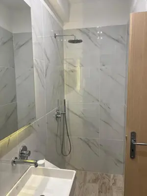 a bathroom with a shower with a sink and a mirror at OSIRIS HOTEL APARTMENTS and STUDIOS in Ialyssos