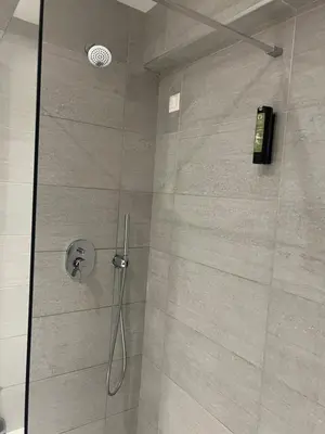 a shower stall with a glass door with a shower at OSIRIS HOTEL APARTMENTS and STUDIOS in Ialyssos