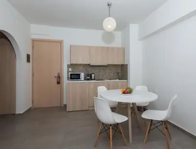 a kitchen with a white table and white chairs at OSIRIS HOTEL APARTMENTS and STUDIOS in Ialyssos