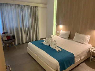a hotel room with a bed with a towel on it at OSIRIS HOTEL APARTMENTS and STUDIOS in Ialyssos