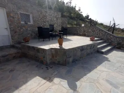 a stone patio with chairs and a table and stairs at Tassos Holiday home in Archangelos