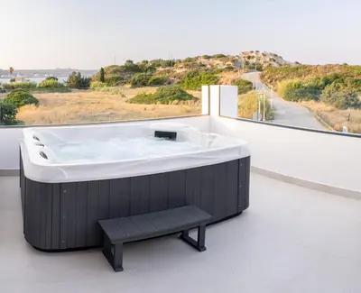 a large bath tub on a balcony with a bench at MelMar Aegean Harmony in Faliraki