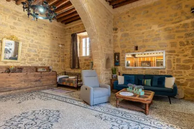 a living room with blue furniture and a stone wall at Finieli's Rustico in Malona Village