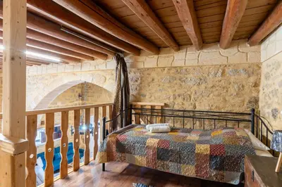 a bedroom with a bed in a room with wooden ceilings at Finieli's Rustico in Malona Village