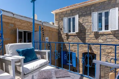 a balcony with a chair and a building at Finieli's Rustico in Malona Village