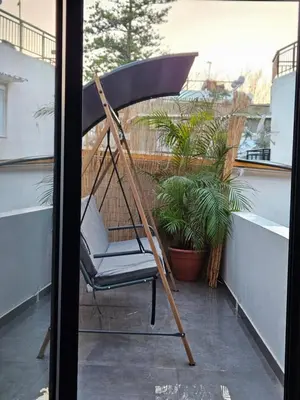 a swinging chair on a balcony with plants at A&A Niohori Home in Rhodes Town