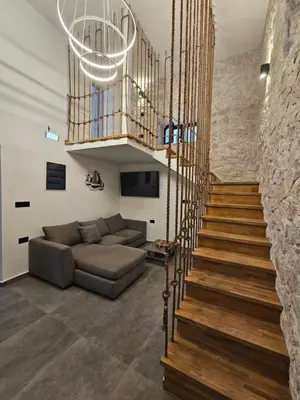 a staircase in a living room with a couch and a chandelier at A&A Niohori Home in Rhodes Town