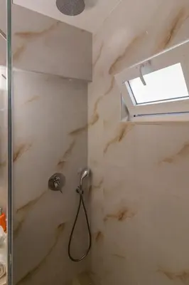a bathroom with a shower with a window at Christina's Apartment in Afantou