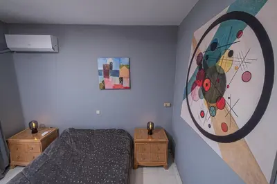 a bedroom with a bed and a painting on the wall at Kounaki Wines Central Square Apartments in Émbonas