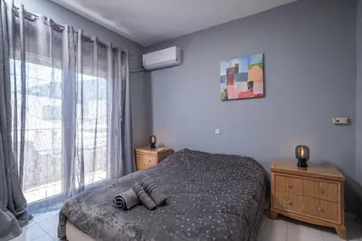 a bedroom with a bed and a large window at Kounaki Wines Central Square Apartments in Émbonas