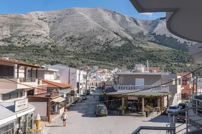 a woman walking down a street in a town with a mountain at Kounaki Wines Central Square Apartments in Émbonas