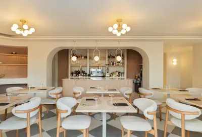 a restaurant with white tables and chairs and a kitchen at Cento Palme in Rhodes Town