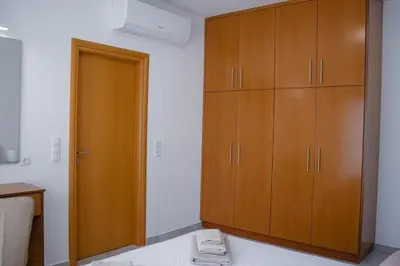a bedroom with wooden cabinets and a bed at ELMA apartment 1 Kremasti in Kremasti