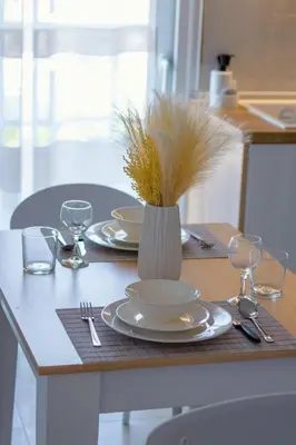 a table with plates and glasses and a vase with grass at ELMA apartment 1 Kremasti in Kremasti