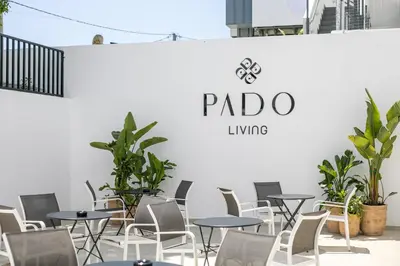 a group of tables and chairs in front of a wall at Pado Living in Faliraki