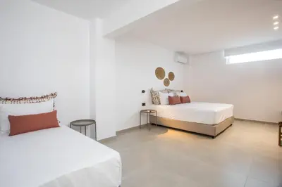 a white room with two beds and two tables at Pado Living in Faliraki