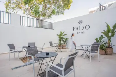 a room with tables and chairs and a woman walking in the background at Pado Living in Faliraki