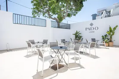 a row of tables and chairs in front of a white wall at Pado Living in Faliraki