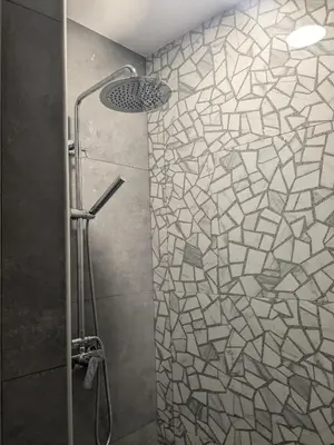 a bathroom with a shower with a mosaic tile wall at Nirea Studio II in Faliraki
