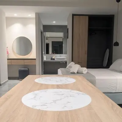 a bedroom with a bed and a table with a bed and a bathroom at Nirea Studio II in Faliraki