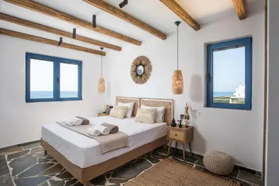 a bedroom with a bed with white walls and windows at Villa Mare Mio, beachfront, newly rennovated in Lachania