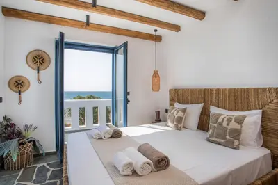 a bedroom with a bed and a balcony with the ocean at Villa Mare Mio, beachfront, newly rennovated in Lachania