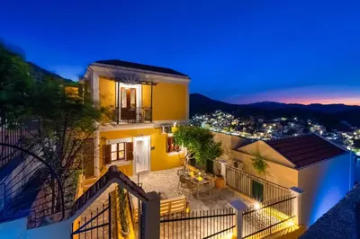 a house with a balcony at night with lights at Elpidas Apartments in Symi