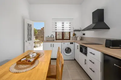 a kitchen with a wooden table and a washing machine at Elpidas Apartments in Symi