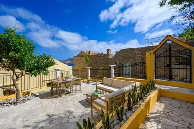 a patio with a table and a bench and a building at Elpidas Apartments in Symi