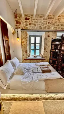 a large white bed in a room with a window at H-aris Seafront Mansion in Halki