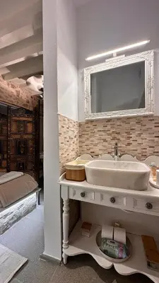 a white bathroom with a sink and a bed at H-aris Seafront Mansion in Halki