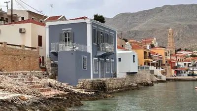 a blue building next to a river with buildings at H-aris Seafront Mansion in Halki