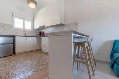 a kitchen with white cabinets and a bar with a stool at Caserma Regina in Rhodes Town