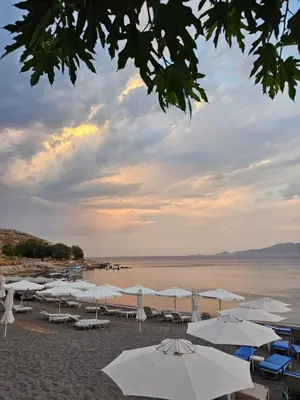 a group of umbrellas and chairs on a beach at Haraki De Sol Beach Apartments in Haraki