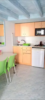 a kitchen with a table and green chairs at Haraki De Sol Beach Apartments in Haraki