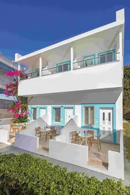 a house with a balcony with tables and chairs at Haraki De Sol Beach Apartments in Haraki