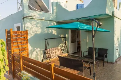 a patio with a blue umbrella and a table and chairs at Private House, Peaceful Stylish Retreat Near Ialisos Beach, up to 5 Guests in Ialyssos