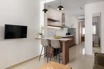 a kitchen and living room with a bar and a tv at Ama Apartments in Rhodes Town