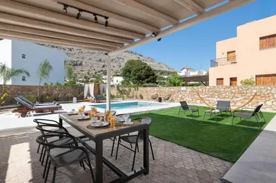 a patio with a table and chairs and a swimming pool at Avia Villa in Pefki Rhodes