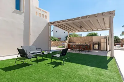 a patio with a lawn with chairs and a kitchen at Avia Villa in Pefki Rhodes