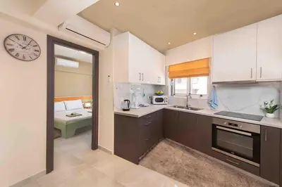 a kitchen with white cabinets and a clock on the wall at Modern Colorful House 1 rhodos in Rhodes Town