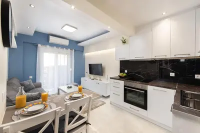 a kitchen with white cabinets and a table with chairs at Modern Colorful House 4 Rhodos in Rhodes Town