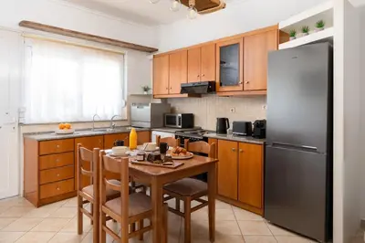 a kitchen with a table and a stainless steel refrigerator at Minimal & Bright Apartment in Ialyssos