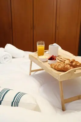 a tray of bread and orange juice on a bed at KMS Summer House Ialisos in Rhodes Town