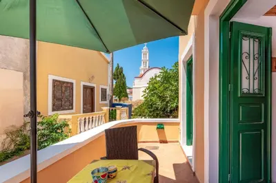 a patio with a table and a green umbrella at Matina's House in Halki