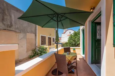 a table with a green umbrella on a balcony at Matina's House in Halki
