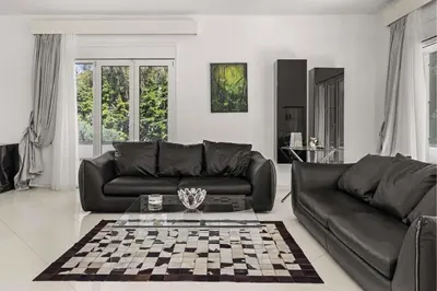 a living room with a black leather couch and a chessboard at Adamas Villa Rhodes in Rhodes Town
