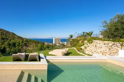 a swimming pool with chairs and a rock wall at Adamas Villa Rhodes in Rhodes Town